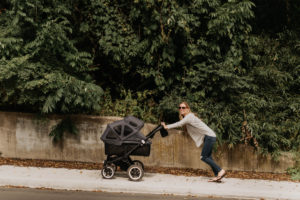 Mother pushing baby carriage up pavement Mother pushing baby carriage up pavement